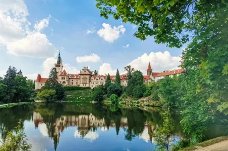 Zámek v parku Průhonice odrazený ve vodě jezera.