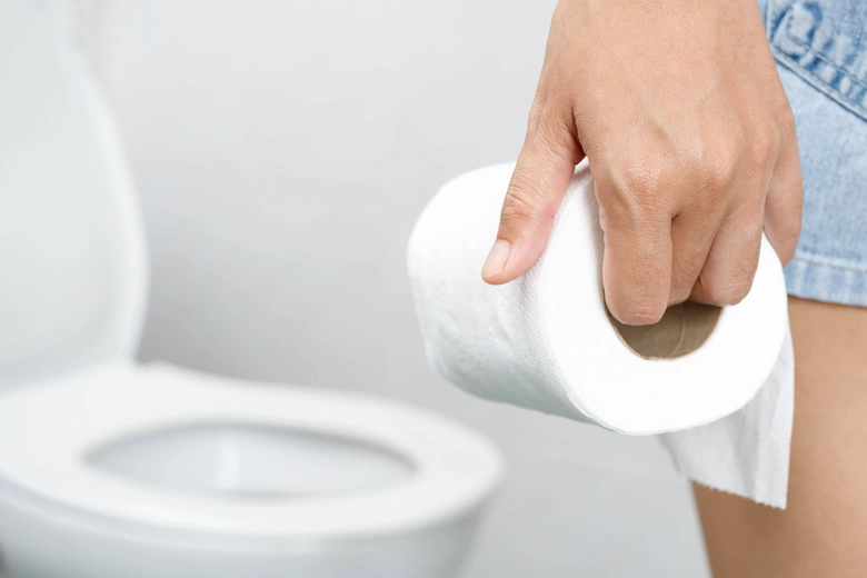 Ruka drží toaletní papír u záchodu při průjmě