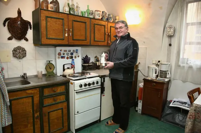 Muž v kuchyni plné starožitností, kde bydlel.