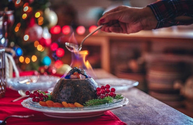 Vánoční pudink s hořícími plameny podáván na vánočním stolu.