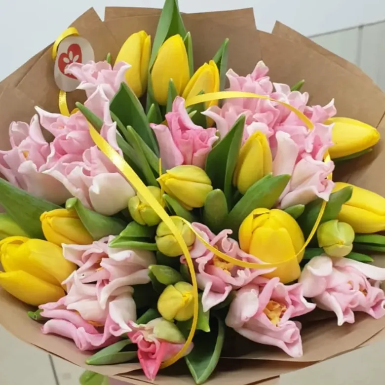 Květinová vazba s žlutými růžovými tulipány v hnědém papíru.