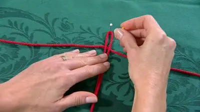 Ruční pletení červené pomlázkové provázky na zeleném pozadí.