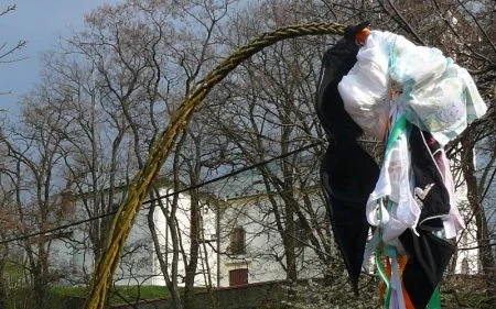 Tradiční pomlázka s květinami a stuhami na venkovském pozadí.