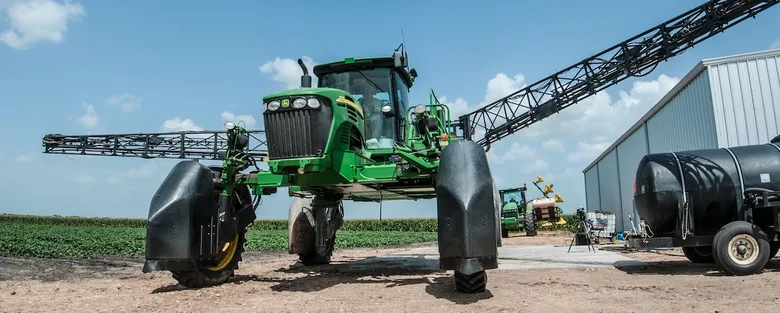 Zelený traktor pro postřik bavlny na poli.
