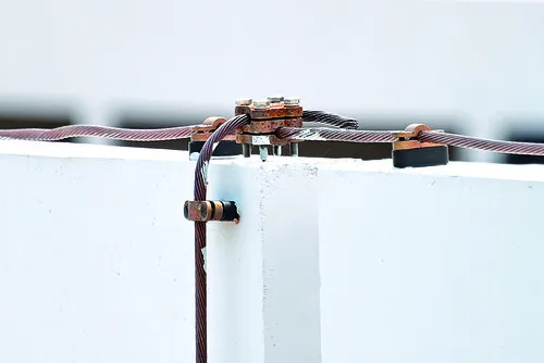 Detailní pohled na hromosvod připevněný ke zdi s kabely.