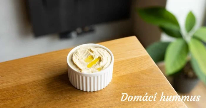 Domácí hummus v bílé misce na dřevěném povrchu.