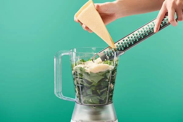 Ruční strouhání sýra do mixéru na domácí pesto.